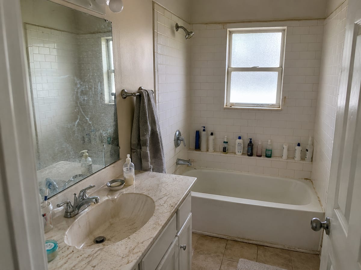 Shower glass and tile grout with hard water film and soap residue before cleaning in Roswell